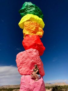 Girl in front of rainbow painted rocks 