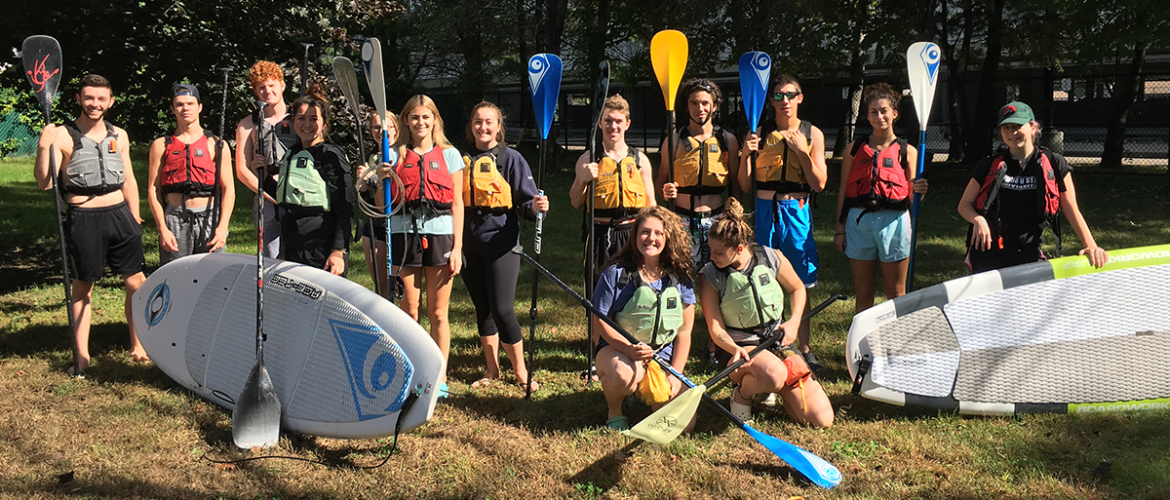 Paddleboard composition class standing with paddles and boards for photo.