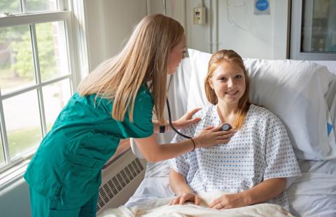 Nursing students using stethoscope on patient