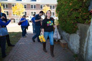 A few students walk in a line holding bags of food for donation.