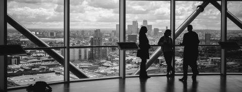 Business people in front of a glass wall overlooking a city.