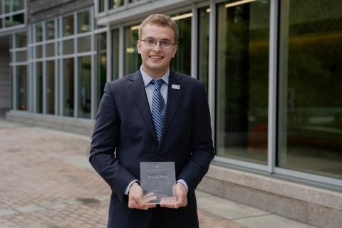 Photo of a young man, Kyle Dimick, holding a small award plaque.