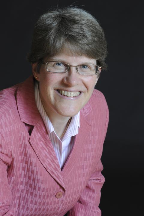 Professional headshot of a woman, Ann Thurston, wearing a pink suit